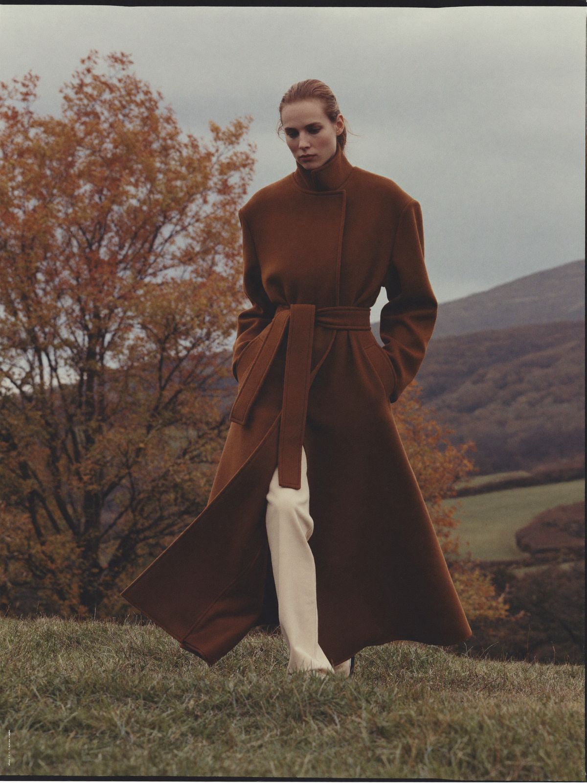 Women's camel coat on an autumn hillside